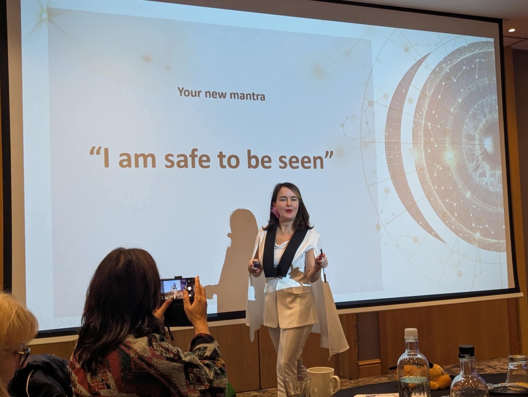 Julia Schmitz presenting at a live workshop, speaking to an audience in front of a presentation screen